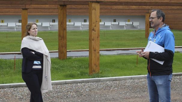 <p>DG-Ministerin Isabelle Weykmans mit Philippe Heck vom nationalen Biathlon-Verband vor dem Schießstand des Langlauf- und Biathlonzentrums, das zurzeit in Herzebösch entsteht.</p>