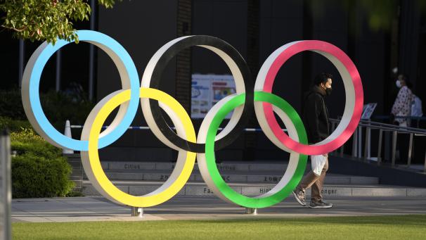 <p>Menschen gehen an den olympischen Ringen, die in Tokiovor dem Japanischen Olympischen Museuminstalliert sind, vorbei.</p>