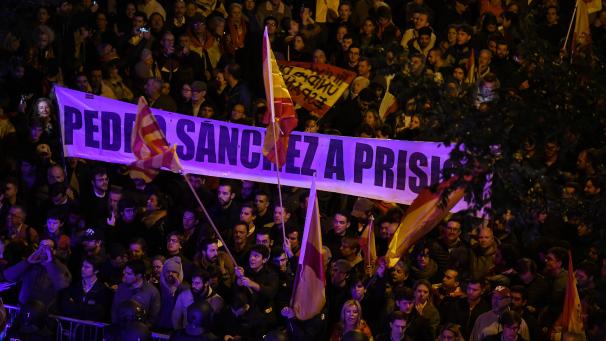 <p>Menschen nehmen an einem Protest gegen ein Abkommen mit den spanischen Separatisten-Parteien vor dem Sitz der sozialistischen Partei PSOE teil und halten ein Transparent mit der Aufschrift „Haft für Pedro Sanchez“.</p>