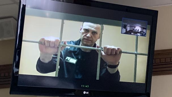 <p>Alexej Nawalny wird in einem Gerichtssaal per Videoverbindung aus dem Gefängnis zugeschaltet und ist auf einem Bildschirm zu sehen.</p>