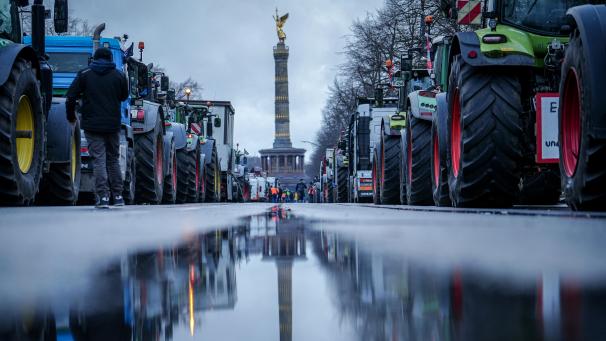 <p>Die Siegessäule und Traktoren spiegeln sich in einer großen Pfütze: Die Proteste richten sich gegen geplante Subventionskürzungen durch die Bundesregierung unter anderem beim Agrardiesel.</p>