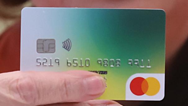 <p>Eine Bezahlkarte wird bei einer Pressekonferenz gezeigt.</p>