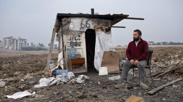 <p>Ein Mann sitzt inmitten eines Abrissareals vor einer provisorischen Hütte, die ihm als Schutz vor der Witterung dient.</p>