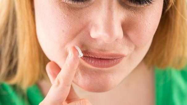 <p>Eine junge Frau trägt eine Pflegecreme auf.</p>