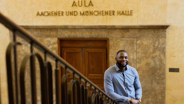 <p>Contimi Kenfack Mouafo, Student der Elektrotechnik an der RWTH Aachen, steht in einem Universitätsgebäude. Der 28-Jährige engagiert sich mit dem Verein „3 E’s 4 Africa“.</p>