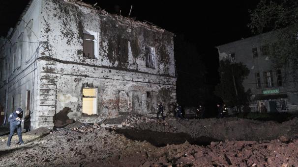 <p>Polizisten stehen vor einem Krater nach einem russischen Raketenangriff auf eine psychiatrische Klinik</p>