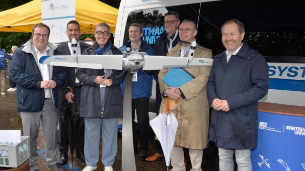 <p>Hinter einer der eingesetzten Drohnen stehen (v.l.) NRW-Minister Oliver Krischer, Daniel Phiesel (BMDV), Sibylle Keupen (Oberbürgermeisterin Aachen), Prof. Dieter Moormann (RWTH), Städteregionsrat Dr. Tim Grüttemeier, Ministerialrat Rudolf Boll (BMDV) und Luc Frank (Bürgermeister Kelmis).</p>