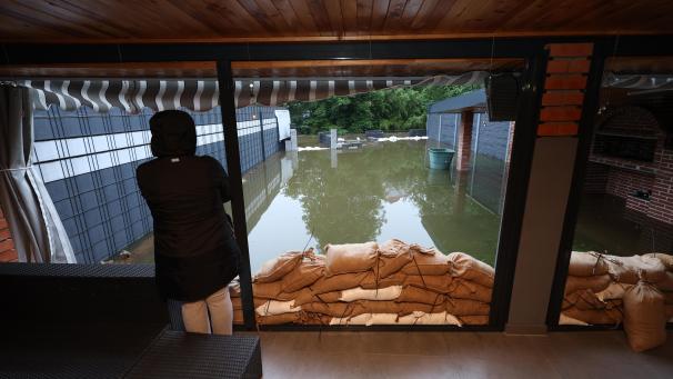 <p>Eine Frau steht in Burgau in einem Wintergarten vor ihrem vom Hochwasser der Mindel überfluteten Garten.</p>