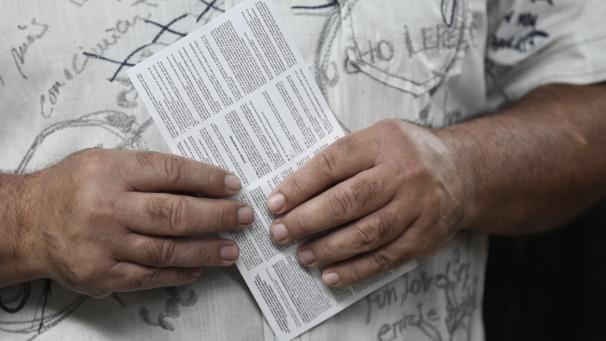 <p>Mit der Wahlaufforderung in der Hand warten auf die Stimmabgabe</p>