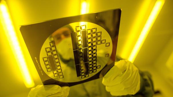 <p>Ein Mann trägt in einem Reinraum eine sogenannte Maske zur Herstellung von Halbleiterstrukturen.</p>