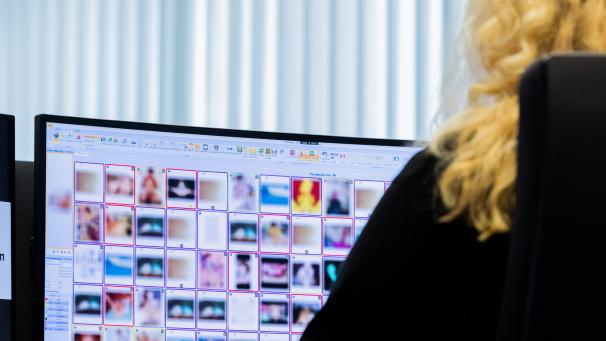 <p>Eine Ermittlerin sitzt vor einem Monitor mit Fotografien, die teilweise sexuellen Missbrauch von Kindern zeigen.</p>