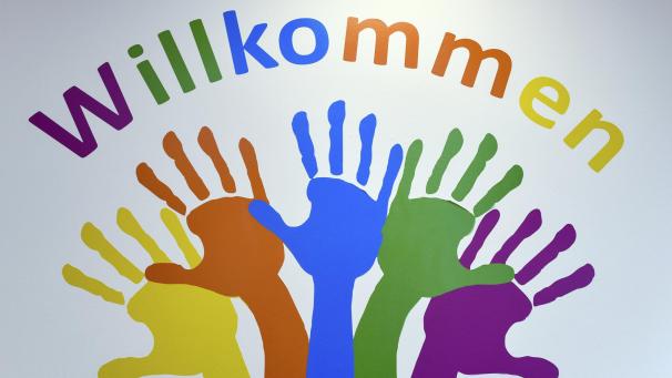 <p>Bunte Hände zieren die Wand eines Integrationszentrums</p>