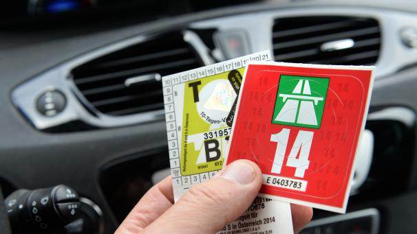<p>Ein Autofahrer hält eine Schweizer Jahresvignette (rechts) in der Hand.</p>
