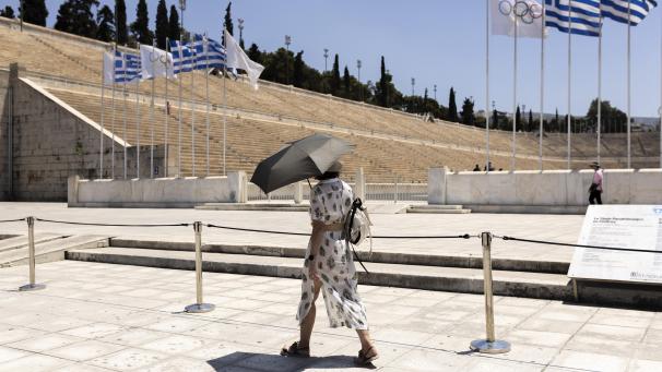 <p>Eine Touristin mit einem Schirm geht vor dem Panathinaiko-Stadion entlang.</p>