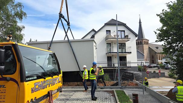 <p>Mit einem Kran wurde der lokale Verteilerkasten des Glasfasernetzes in der Gemeinde Amel am Freitagmorgen an seinen Standort am Rande des neuen Mitfahrparkplatzes hinter dem Gemeindehaus gehievt.</p>