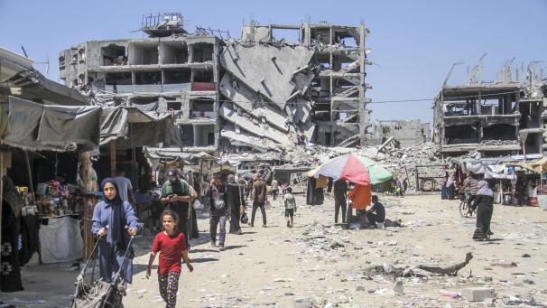 <p>Menschen stehen inmitten von Trümmern im Flüchtlingslager Jabalia im Norden des Gazastreifens.</p>