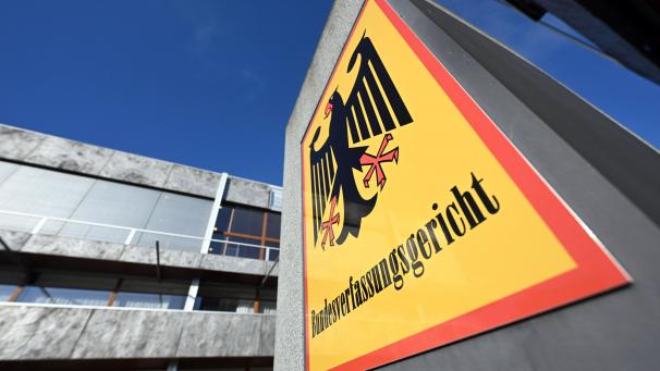 <p>Ein Hinweisschild mit Bundesadler und dem Schriftzug Bundesverfassungsgericht, aufgenommen vor dem Bundesverfassungsgericht.</p>