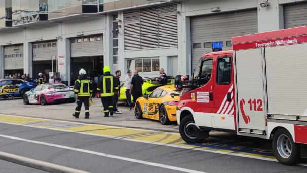 <p>Feuerwehrleute laufen vor Box 27 in der Boxengasse des Nürburgrings.</p>
