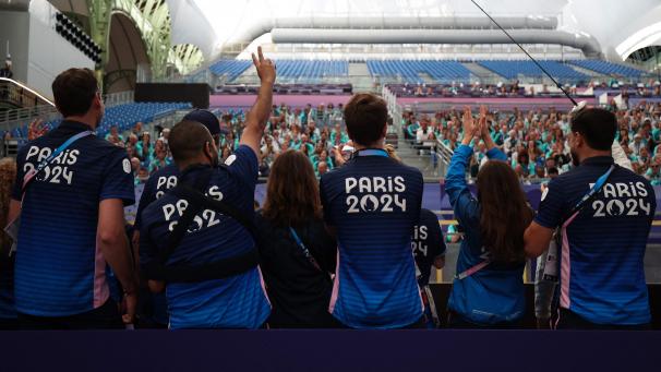 <p>Mitarbeiter der Olympischen und Paralympischen Spiele Paris 2024 begrüßen die Freiwilligen, die auf der Tribüne sitzen, während sie an einer Trainingseinheit im Grand Palais teilnehmen.</p>