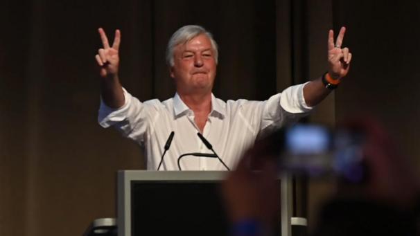 <p>Jürgen Elsässer, Herausgeber des rechtsextremen Monatsmagazins Compact, zeigt ein Victory-Zeichen mit den Händen. Auf dem Parteitag soll der Landesvorstand der AfD Sachsen-Anhalt gewählt werden (Screenshot aus einem Video).</p>