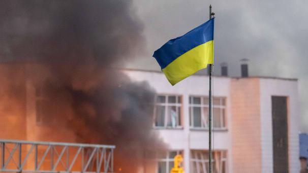 <p>Die ukrainische Flagge weht über dem dichten Rauch, der von einem Feuer nach einem russischen Raketenangriff aufsteigt.</p>