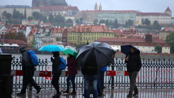 <p>Menschen spazieren im Regen in der Nähe der Moldau in Prag.</p>