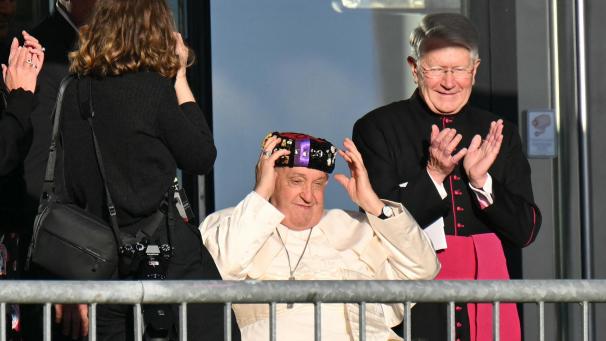 <p>Papst Franziskus setzt die Calotte auf, die er von Studenten der UCLouvain als Geschenk erhalten hat.</p>