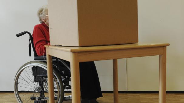 <p>Eine Wählerin im Rollstuhl gibt in einem Wahllokal ihre Stimme ab.</p>
