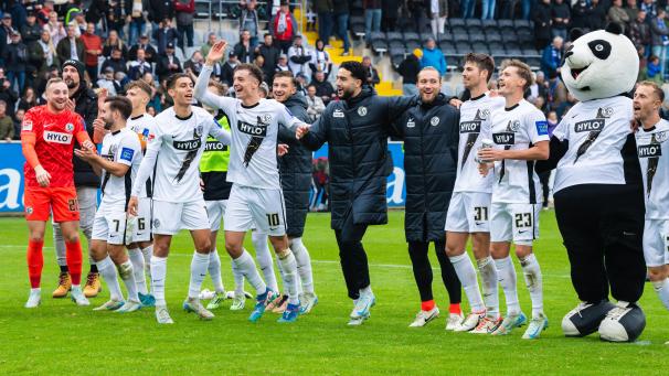 <p>Die Elversberger Fisnik Asllani (l-r), Mohammad Mahmoud, Maximilian Rohr und Carlo Sickinger bejubeln den Sieg mit ihren Teamkollegen und dem Maskottchen. Nein, es ist nicht Eupi von der AS Eupen, sondern Pandabär Paul.</p>