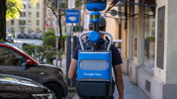 <p>Ein Mann geht mit einem Google-Maps-Rucksack durch die Strassen.</p>