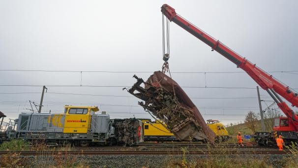 <p>Ein zerstörter Wagen wird von einem Kran von den Gleisen gehoben.</p>