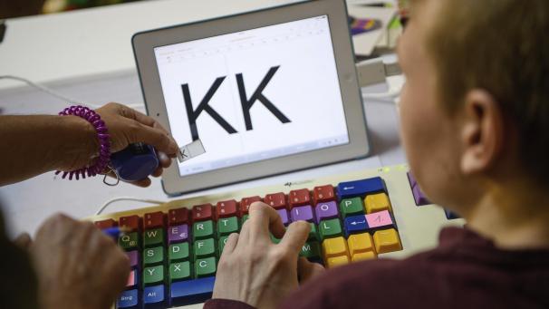 <p>Eine Therapeutin übt mit einem autistischen Kind das Erkennen und Schreiben von Buchstaben auf einer Tastatur.</p>