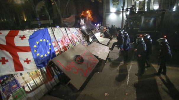 <p>Polizisten stehen in Tiflis neben einer Barrikade, die von Demonstranten während einer Kundgebung vor dem Parlamentsgebäude errichtet wurde.</p>