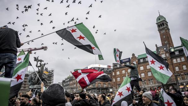 <p>Menschen schwenken in Kopenhagen Fahnen der syrischen Opposition auf dem Rathausplatz, nach dem Sturz des bisherigen syrischen Machthabers al-Assad.</p>