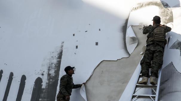 <p>Syrische Oppositionskämpfer entfernen ein Schild mit einem Bild des syrischen Präsidenten Baschar al-Assad am internationalen Flughafen von Aleppo.</p>