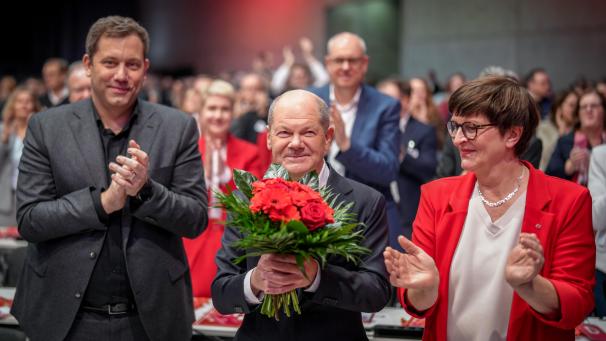 <p>Bundeskanzler Olaf Scholz (SPD, Mitte) lächelt nach seiner Wahl zum SPD-Kanzlerkandidaten beim außerordentlichen SPD-Bundesparteitag neben Saskia Esken, SPD-Bundesvorsitzende, und Lars Klingbeil, SPD-Bundesvorsitzender.</p>
