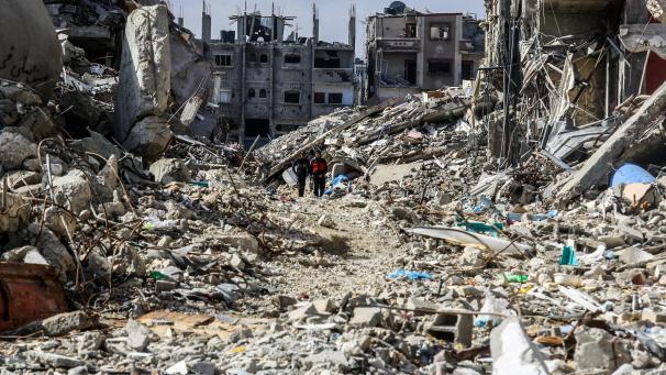 <p>Palästinenser gehen an zerstörten Häusern im Stadtteil Shaboura im Zentrum von Rafah vorbei, wenige Tage nach Inkrafttreten der Waffenruhe zwischen Israel und der Hamas.</p>
