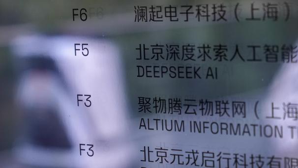 <p>Ein KI-Roboter bewegt sich vorbei an einer Informationstafel des Unternehmens DeepSeek für Smartphone-Apps in Peking.</p>