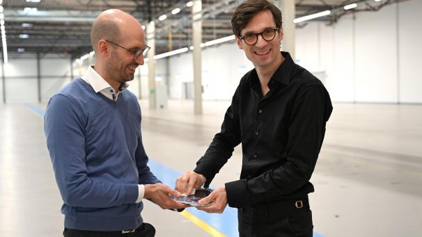 <p>Die beiden Gründer der Halbleiter-Firma Black Semiconductor, der jetzige Finanzchef Sebastian Schall (links) und sein Bruder und Firmenchef Daniel Schall, stehen in der noch leeren Halle ihrer Firma, wo im Laufe dieses Jahres Reinräume zur Halbleiter-Produktion installiert werden sollen. Sie putzen eine Plastikbox, in der ein Wafer liegt.</p>