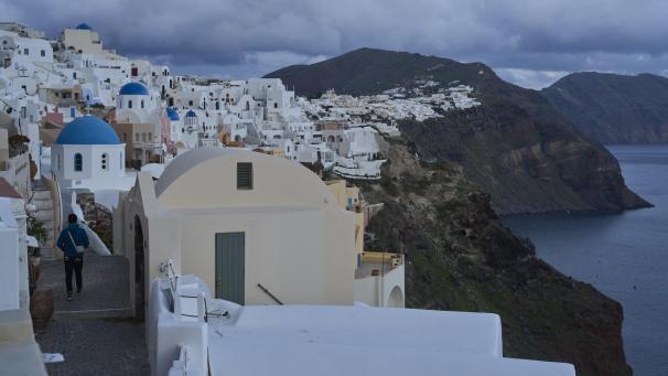 <p>Ein Tourist nähert sich einer orthodoxen Kirche mit blauer Kuppel in Oia auf der erdbebengeschädigten Insel Santorini.</p>