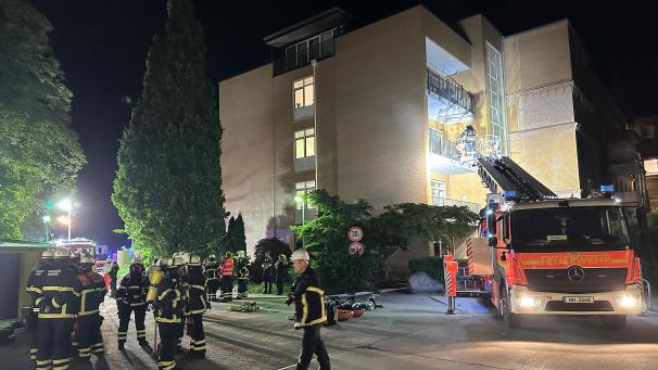 <p>Feuerwehrleute mit Atemschutzgerät und einem Leiterwagen arbeiten am Marienkrankenhaus im Hamburger Stadtteil Hohenfelde. Die Flammen seien von der Geriatrie im Erdgeschoss der Klinik auf das erste Obergeschoss übergeschlagen, hieß es. Feuerwehrleute versuchten Menschen über Fenster ins Freie zu retten.</p>