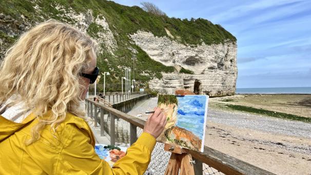 <p>Mit Pinseltrichen fängt eine Frau in der Normandie die silbrigen Lichtreflexe auf den steilen Kreidefelsen ein.</p>