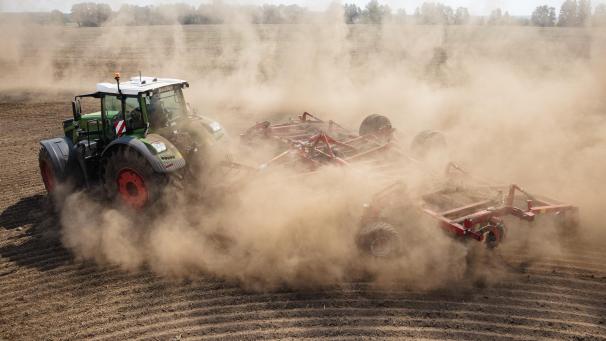 <p>A tractor with an agricultural implement attached drives across a parched field as it raises a cloud of dust near Beelitz, eastern Germany, on August 18, 2022.<br />
JENS SCHLUETER / AFP</p>
