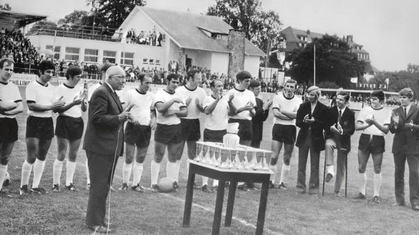 <p>Am 6. September 1970 erhält die AS Eupen den Pappaert-Pokal. Im Hintergrund ist u. a. das heutige Vereinslokal „Penalty“ zu erkennen.</p>
