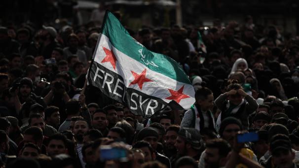 <p>Menschen schwenken eine Fahne der syrischen Opposition während einer Massendemonstration zum zehnten Jahrestag des Beginns des syrischen Bürgerkriegs.</p>