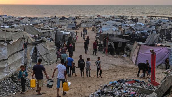 <p>Vertriebene Palästinenser gehen durch ein behelfsmäßiges Lager am Strand von Gaza-Stadt.</p>