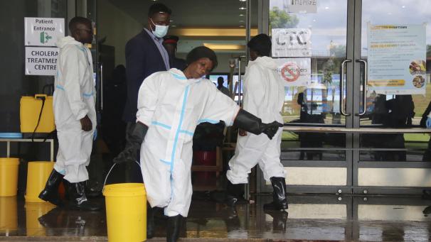 <p>Ein Arbeiterin trägt einen Eimer mit Desinfektionsmittel aus einem Cholera-Behandlungszentrum.</p>