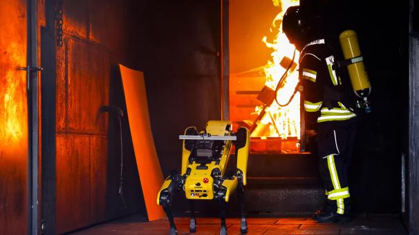 <p>Der KI-Roboter «Byte« und Gruppenführer René Heise von der Landesfeuerwehrschule in Harrislee bei Flensburg stehen vor einem Feuer in einem Container.</p>