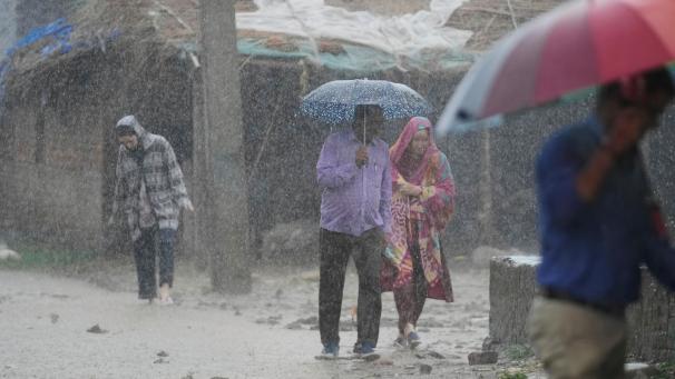 <p>Indien, Jammu: Menschen gehen bei starkem Regen durch die Stadt.</p>