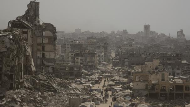 <p>Menschen gehen in Gaza-Stadt eine Straße entlang, die von Gebäuden umgeben ist, die durch israelische Bombardierungen zerstört wurden.</p>